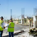 مقاول الدمام المحترف لأعمال البناء والتشطيب بأعلى جودة 4 Rear view of male and female architects working on blueprint at construction site